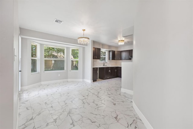 unfurnished living room with a sink, visible vents, baseboards, marble finish floor, and an inviting chandelier