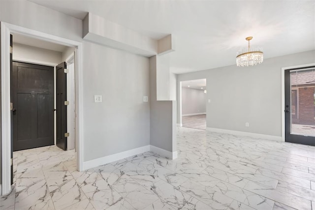 empty room with marble finish floor, baseboards, and an inviting chandelier