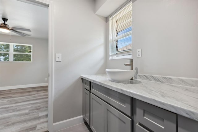 bathroom with a ceiling fan, wood finished floors, vanity, and baseboards