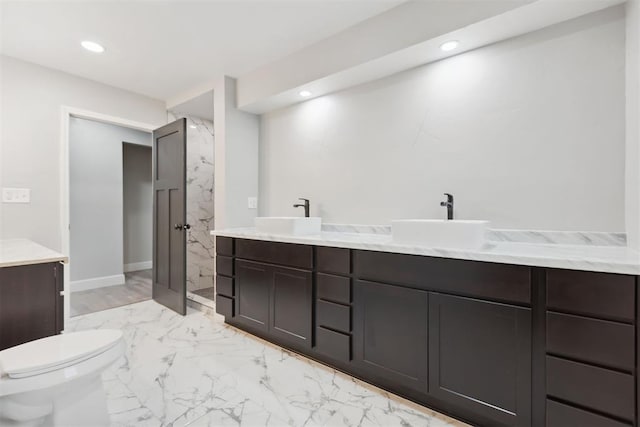 bathroom with double vanity, marble finish floor, and a sink