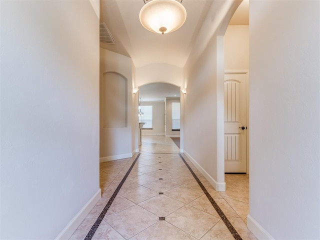 hallway featuring arched walkways, visible vents, and baseboards