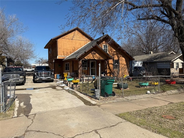 chalet / cabin with a fenced front yard and concrete driveway