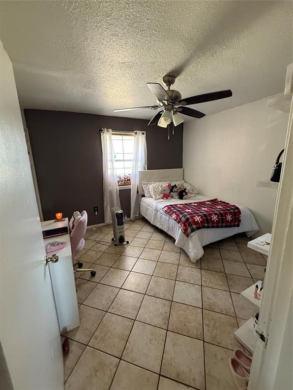 505 SE 18th St, Oklahoma City, OK 73129 - bedroom featuring light tile patterned floors, a textured ceiling, and a ceiling fan