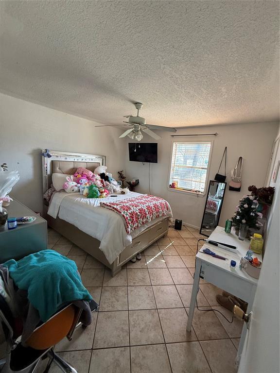 505 SE 18th St, Oklahoma City, OK 73129 - bedroom featuring a ceiling fan, a textured ceiling, and light tile patterned floors