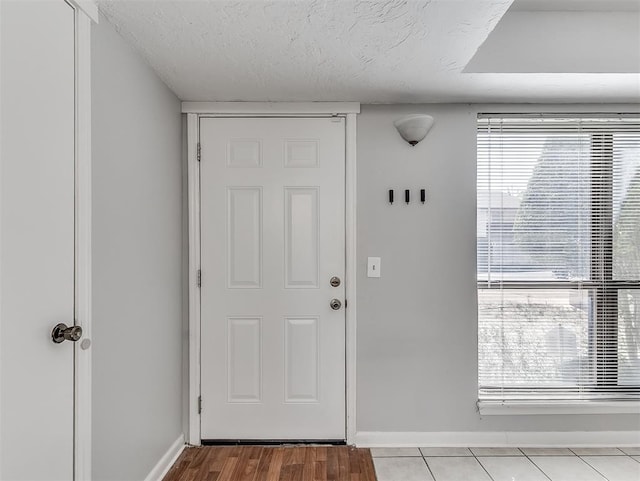 foyer entrance with plenty of natural light, baseboards, and a textured ceiling