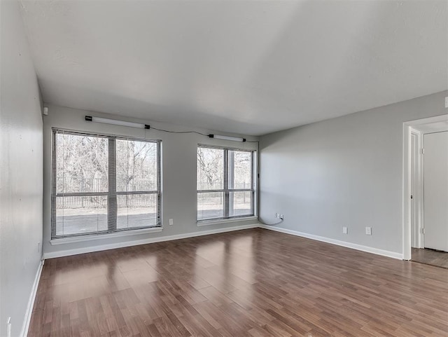 spare room featuring baseboards and wood finished floors