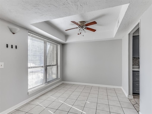 unfurnished room featuring a ceiling fan, baseboards, a tray ceiling, and a textured ceiling