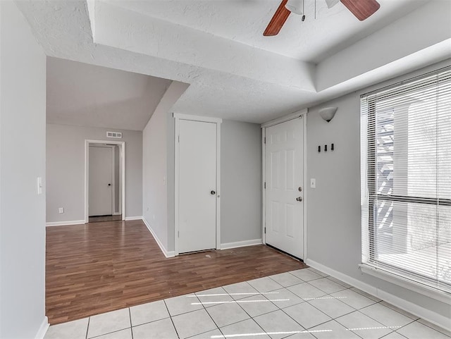 foyer entrance featuring ceiling fan, a textured ceiling, baseboards, and light tile patterned floors