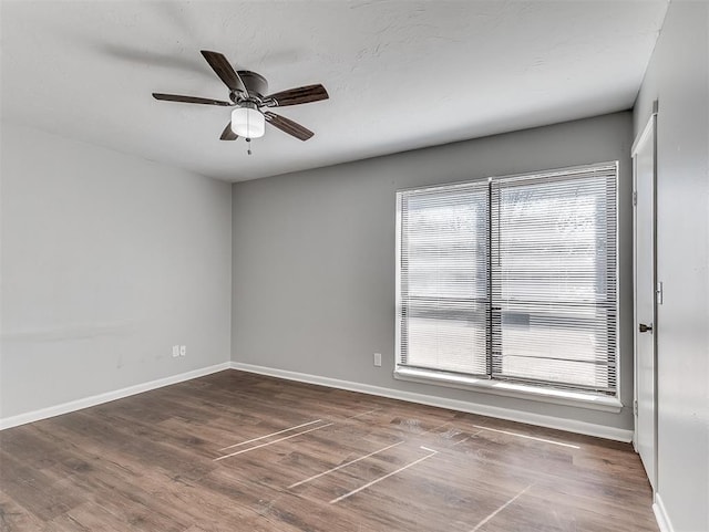 spare room featuring ceiling fan, baseboards, and wood finished floors