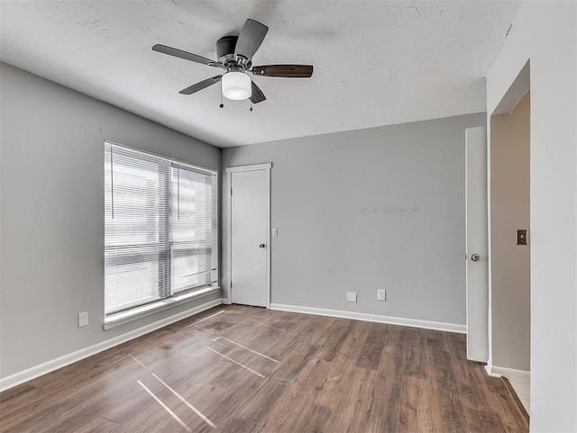 spare room with ceiling fan, a textured ceiling, wood finished floors, and baseboards