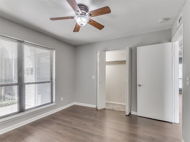 unfurnished bedroom featuring dark wood-style floors, a closet, visible vents, and baseboards