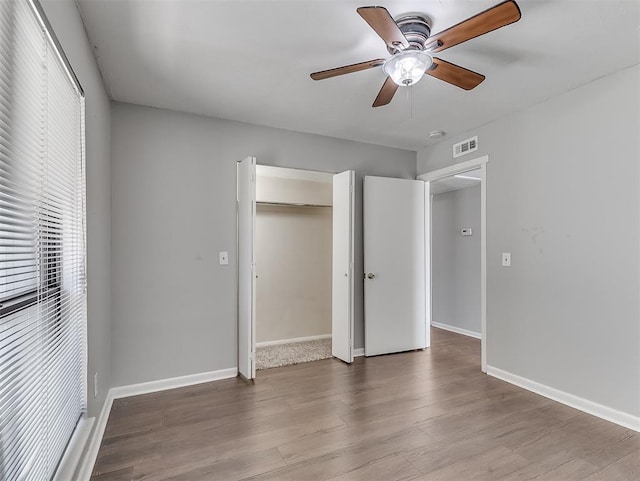 unfurnished bedroom with a closet, visible vents, baseboards, and wood finished floors