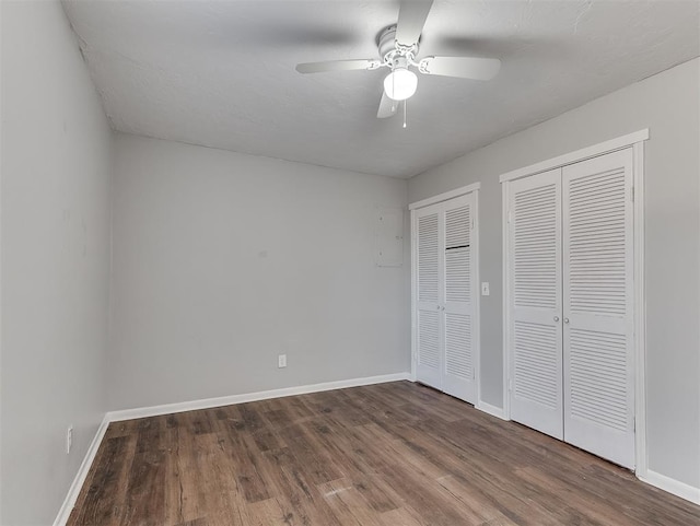 unfurnished bedroom featuring baseboards, wood finished floors, and multiple closets