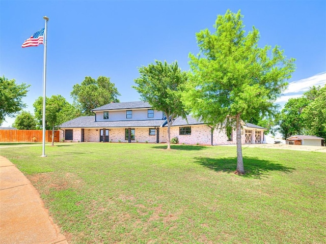 view of front of house featuring brick siding, a front yard, and fence