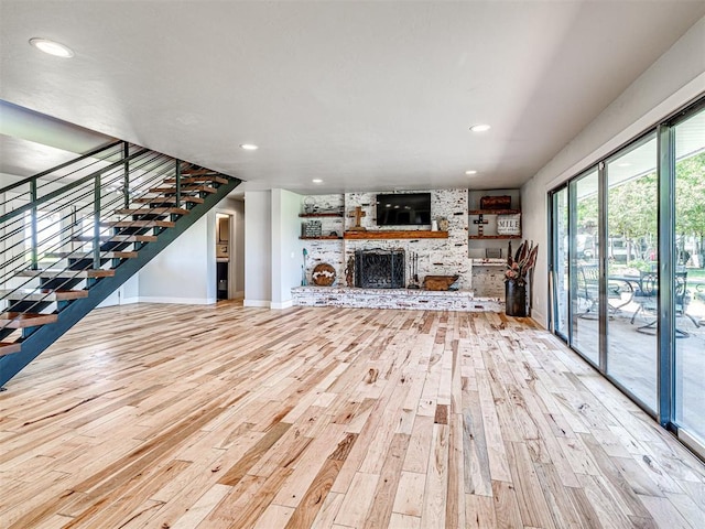 unfurnished living room with a large fireplace, baseboards, stairway, wood finished floors, and recessed lighting