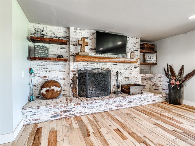 unfurnished living room featuring a brick fireplace, baseboards, and hardwood / wood-style floors