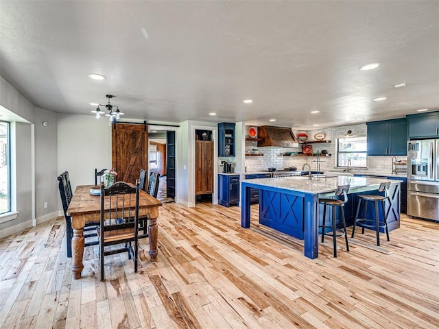 dining space featuring recessed lighting, baseboards, light wood finished floors, and a barn door