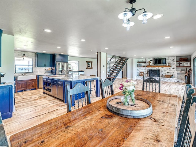 dining area featuring light wood-style floors, recessed lighting, a fireplace, and stairs