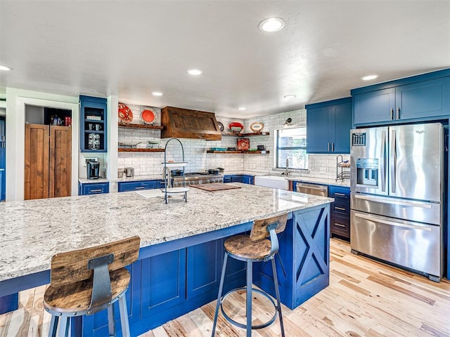 kitchen featuring open shelves, light wood-style floors, blue cabinets, and stainless steel appliances