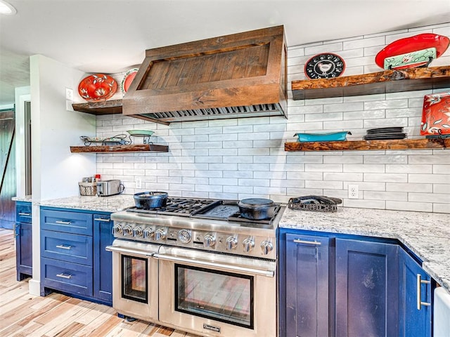 kitchen with range with two ovens, open shelves, decorative backsplash, blue cabinets, and premium range hood