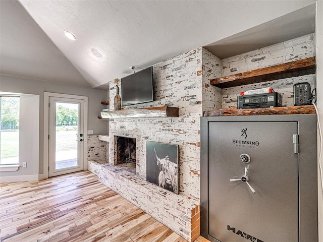 living area with lofted ceiling, a brick fireplace, and wood finished floors