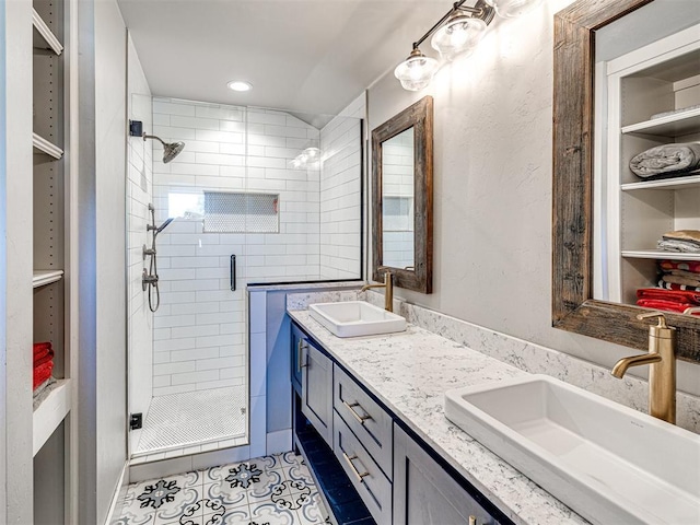 bathroom featuring double vanity, tile patterned floors, a sink, and a shower stall