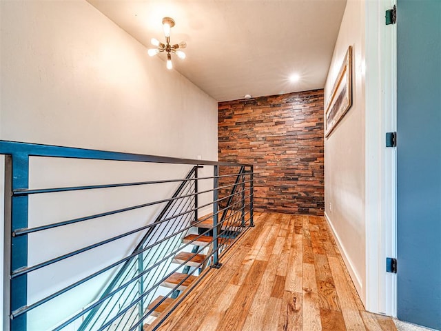 hallway featuring light wood-style floors, an upstairs landing, and an inviting chandelier