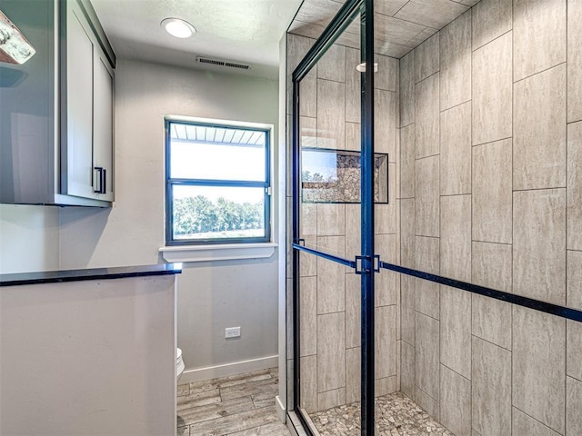 bathroom with baseboards, visible vents, toilet, wood finished floors, and a shower stall