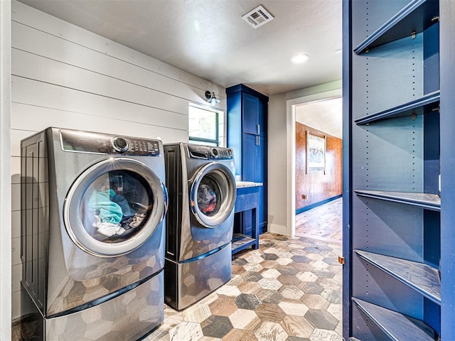 clothes washing area featuring washer and dryer, cabinet space, and visible vents