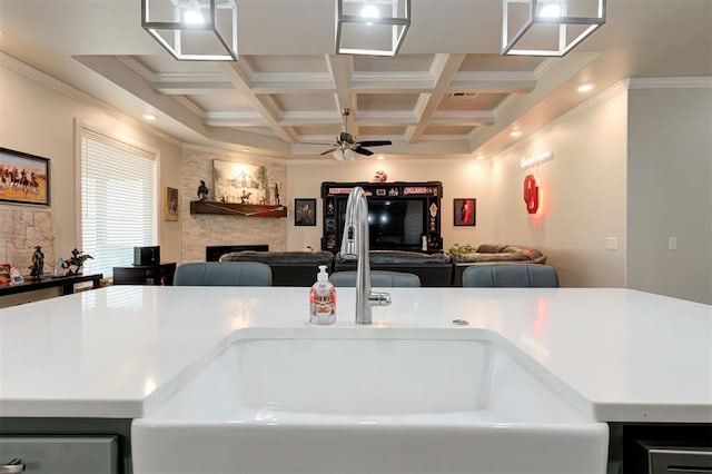 kitchen with coffered ceiling, open floor plan, beamed ceiling, and a stone fireplace