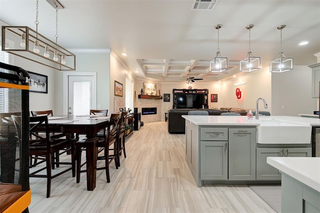 kitchen with light countertops, visible vents, gray cabinetry, a large fireplace, and a sink