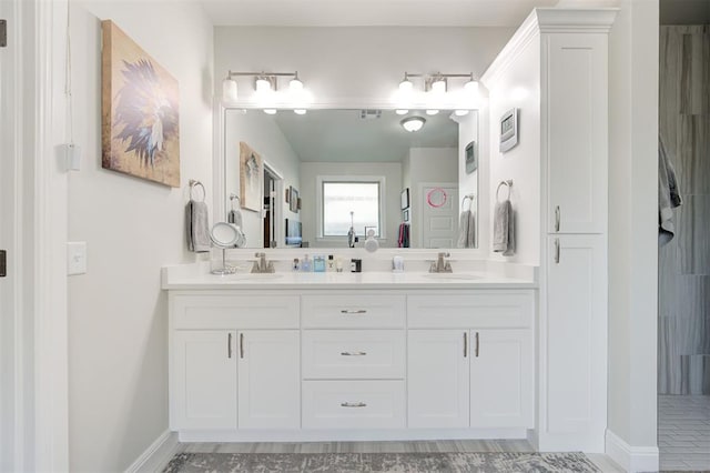 full bathroom featuring double vanity, a sink, and baseboards