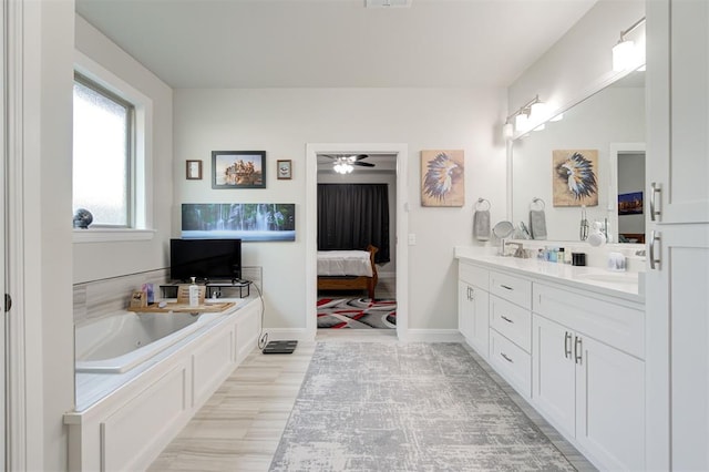 ensuite bathroom featuring double vanity, baseboards, ensuite bath, a garden tub, and a sink