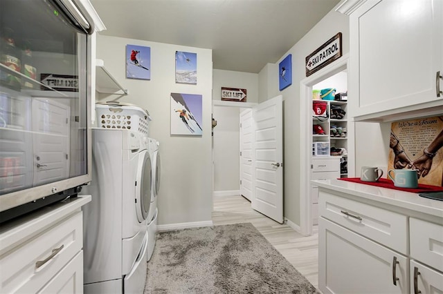 laundry area featuring cabinet space, baseboards, separate washer and dryer, and light wood-style floors