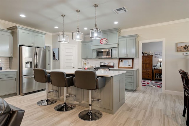 kitchen featuring a breakfast bar area, stainless steel appliances, gray cabinets, light countertops, and visible vents