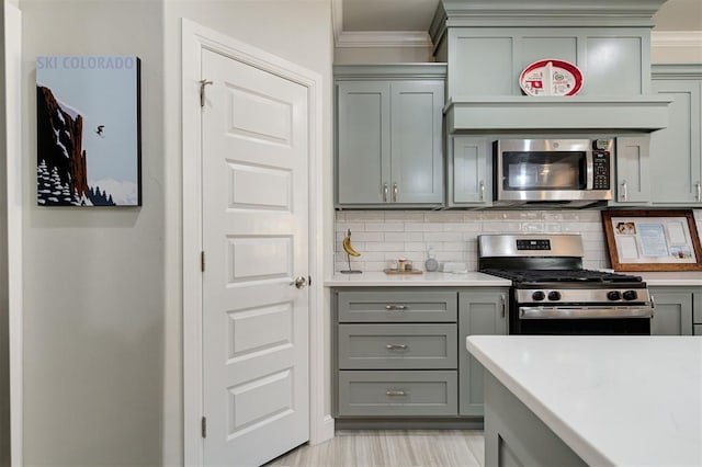 kitchen featuring stainless steel appliances, light countertops, ornamental molding, and gray cabinetry