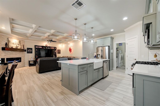 kitchen featuring a fireplace, stainless steel appliances, light countertops, visible vents, and a sink