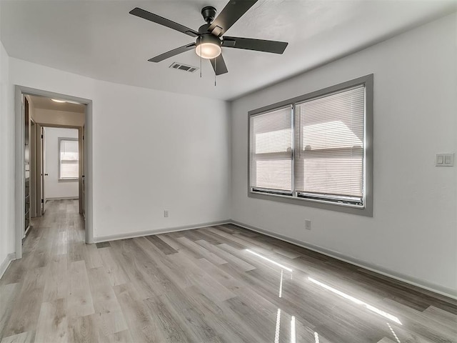 unfurnished room with baseboards, visible vents, ceiling fan, and light wood finished floors