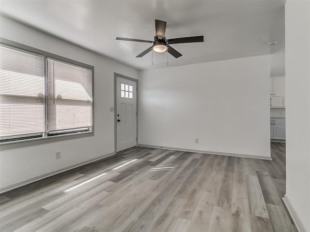 interior space with light wood-style flooring, baseboards, and ceiling fan