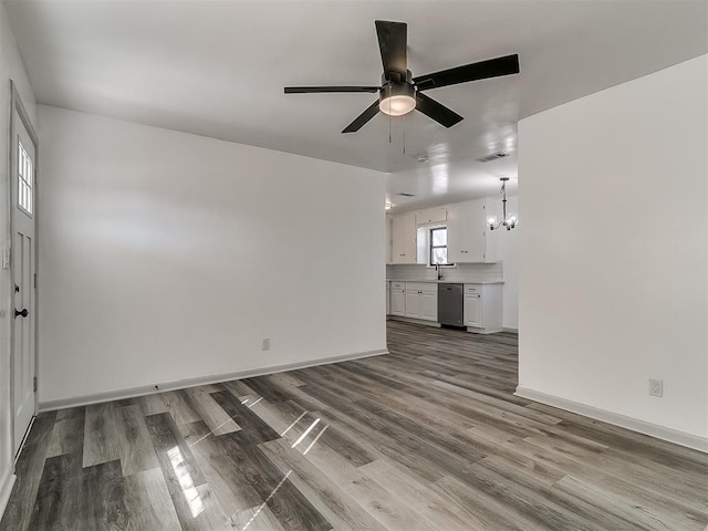 unfurnished living room with dark wood-style flooring, visible vents, a sink, and baseboards