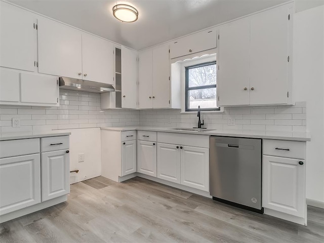 kitchen with tasteful backsplash, white cabinets, stainless steel dishwasher, under cabinet range hood, and a sink