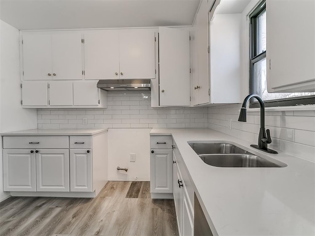 kitchen featuring light countertops, white cabinetry, a sink, and light wood-style flooring