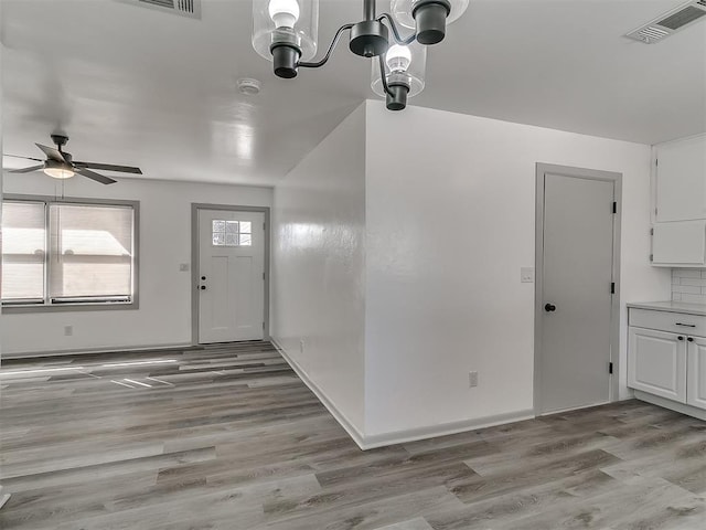 foyer featuring visible vents, light wood-style flooring, baseboards, and ceiling fan with notable chandelier