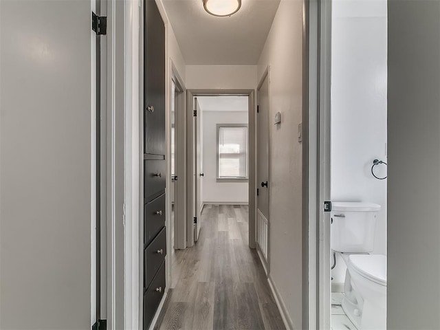 hallway with light wood-type flooring and baseboards