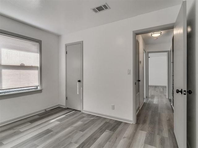 empty room with wood finished floors, visible vents, and baseboards