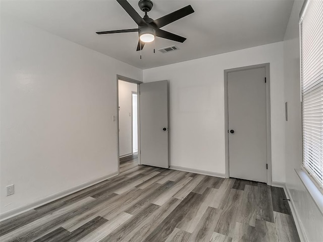 unfurnished bedroom featuring a ceiling fan, baseboards, visible vents, and wood finished floors