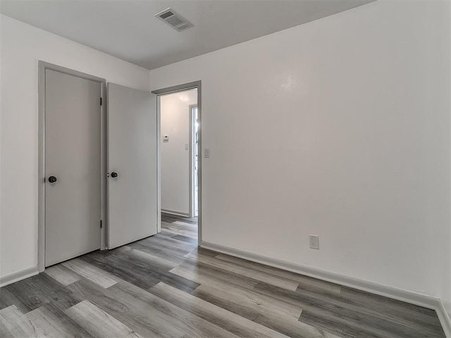 unfurnished room featuring wood finished floors, visible vents, and baseboards