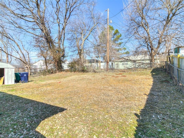 view of yard featuring an outbuilding, a fenced backyard, and a storage unit