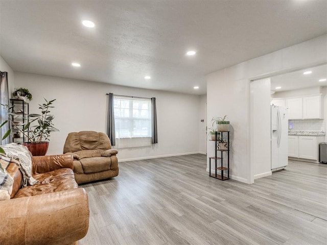 living room featuring recessed lighting, baseboards, and light wood finished floors
