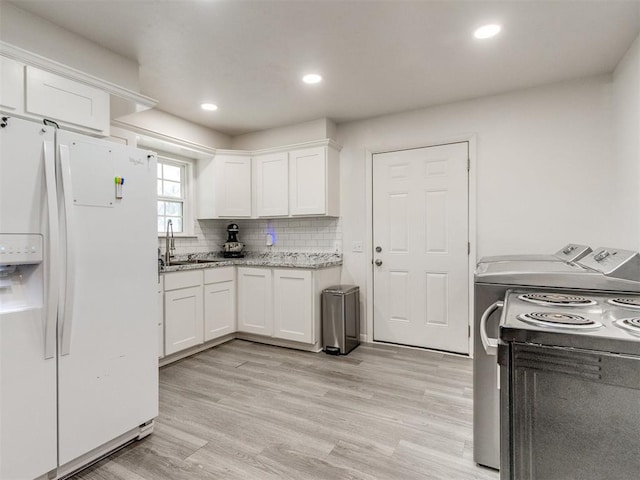 kitchen featuring a sink, white cabinets, electric range oven, white fridge with ice dispenser, and light wood finished floors